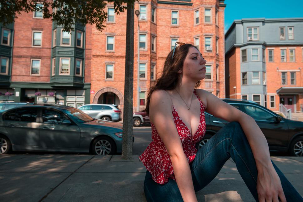 Free Image of Urban scene with a woman sitting by the street 