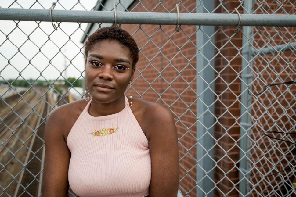 Free Image of Portrait of young woman against a fence 
