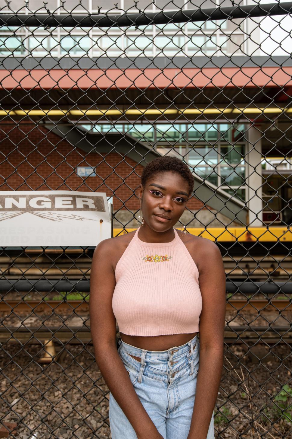 Free Image of Woman in front of a chain-link fence 