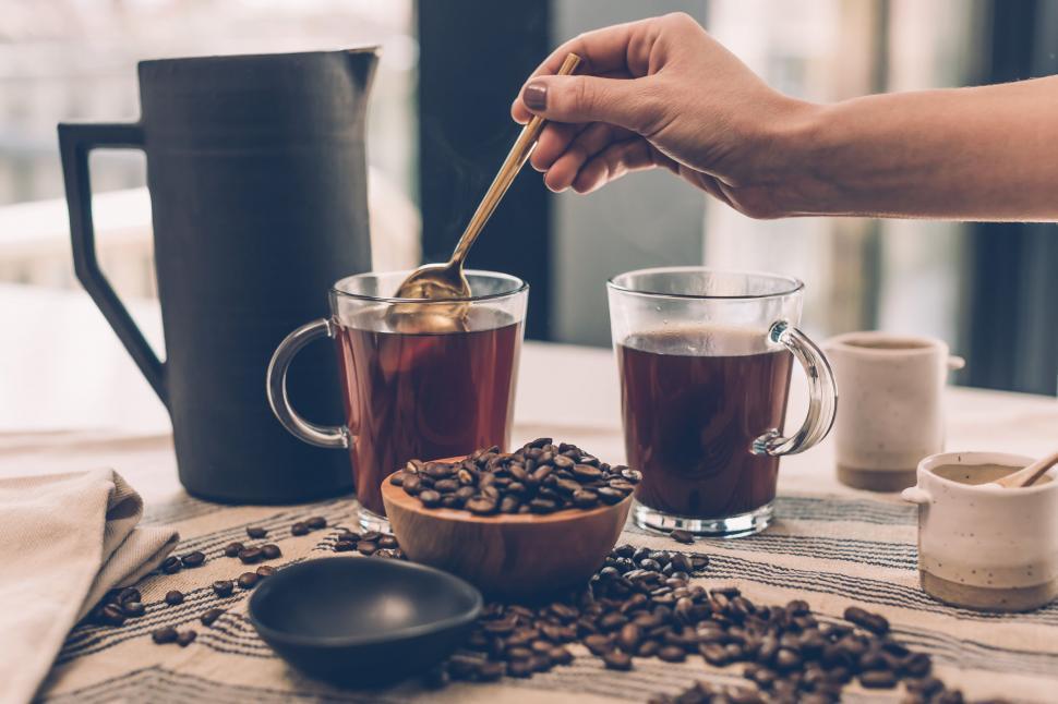 Free Image of Hand pouring honey into tea near beans 