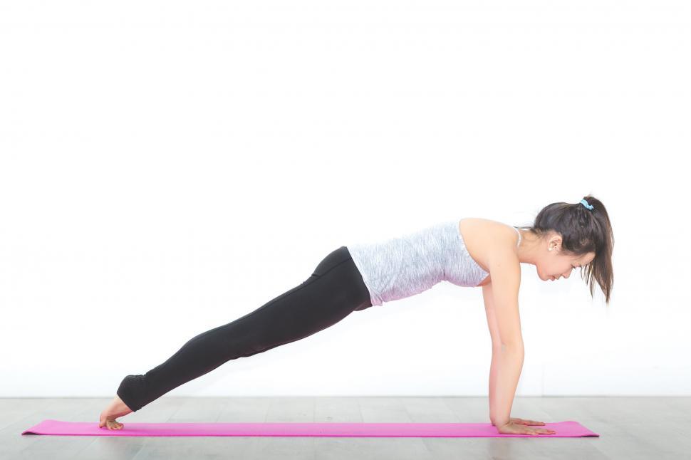 Woman in plank pose on pink yoga mat