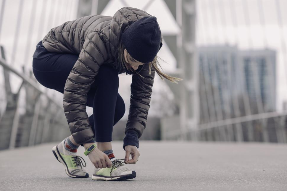 Free Image of Woman tying shoelaces on a city bridge 
