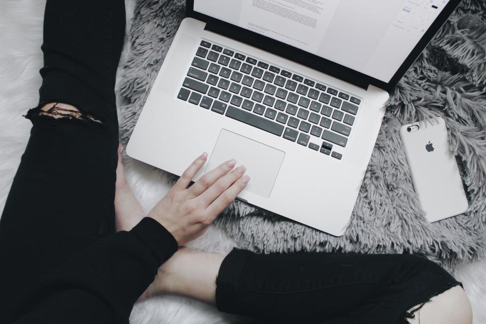 Free Image of Woman working on a laptop with a phone nearby 