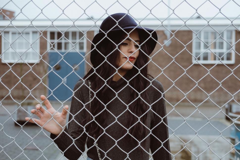 Free Image of Person behind chain-link fence with obscured face 