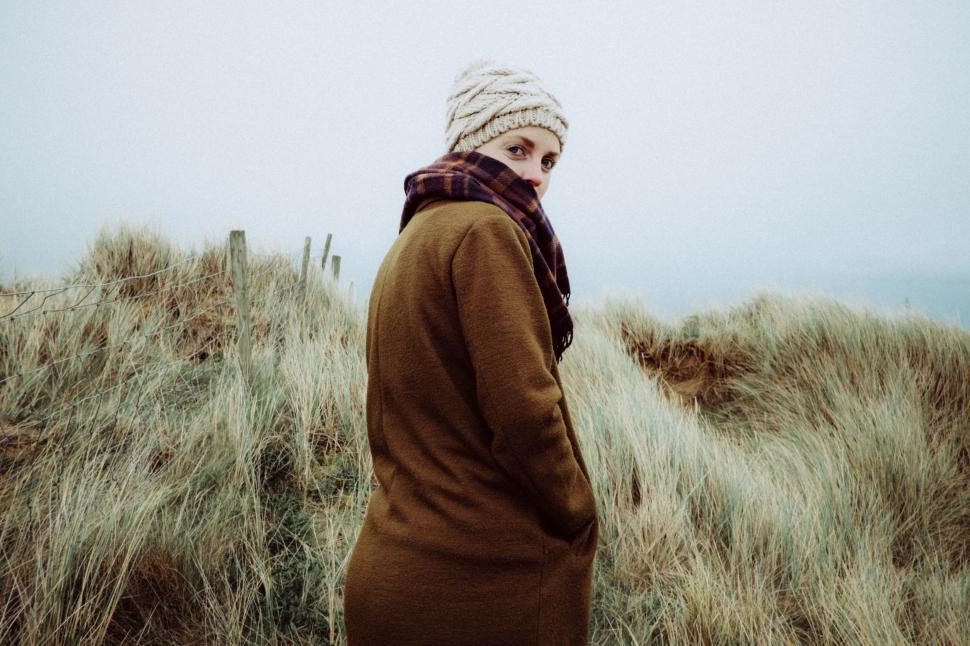 Free Image of Person in coat standing by beach dunes 