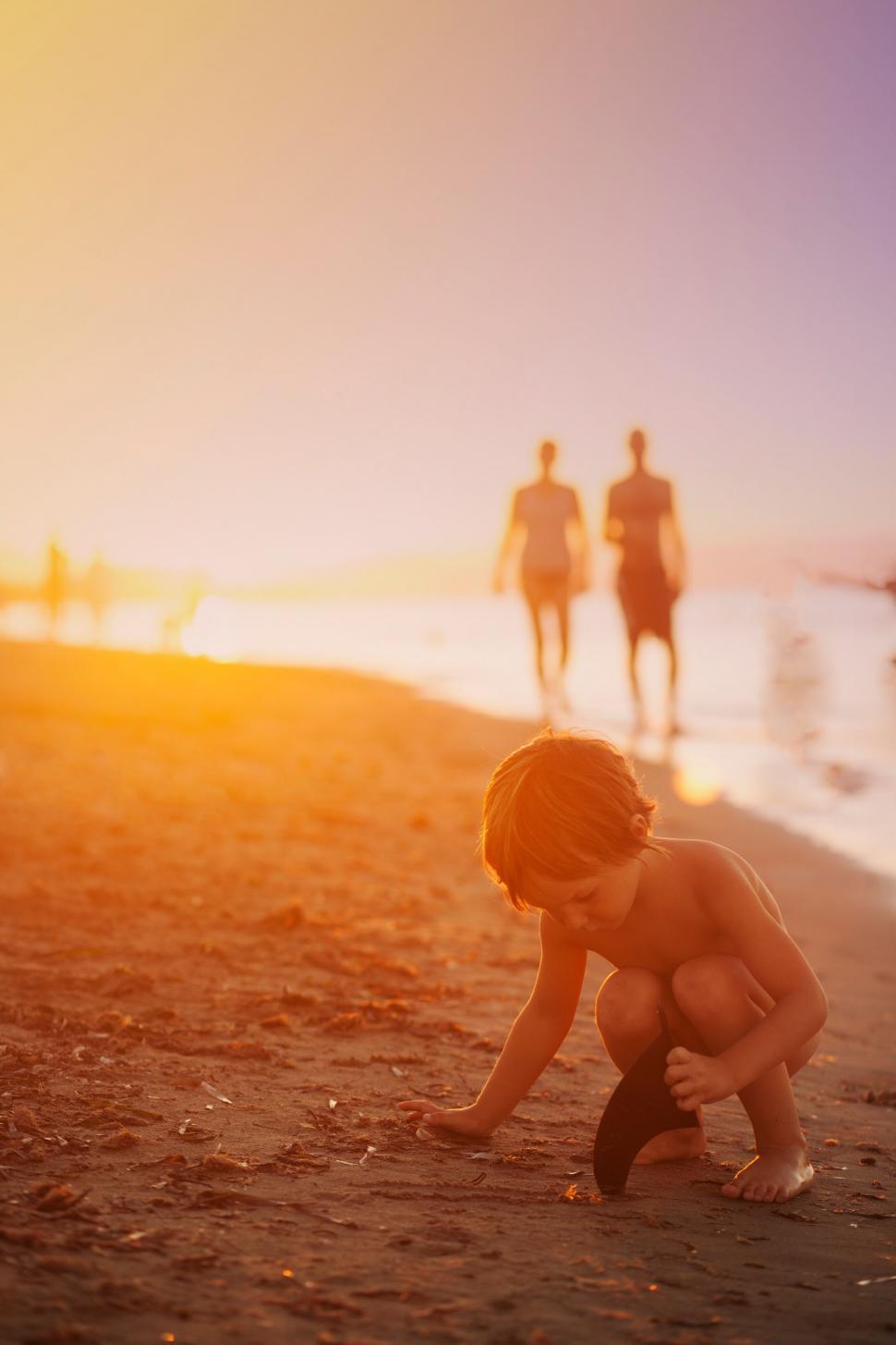 Free Image of Beach exploration at sunset with family in distance 