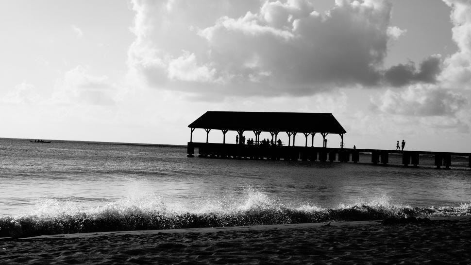 Free Image of Silhouetted pier against a stark seascape 