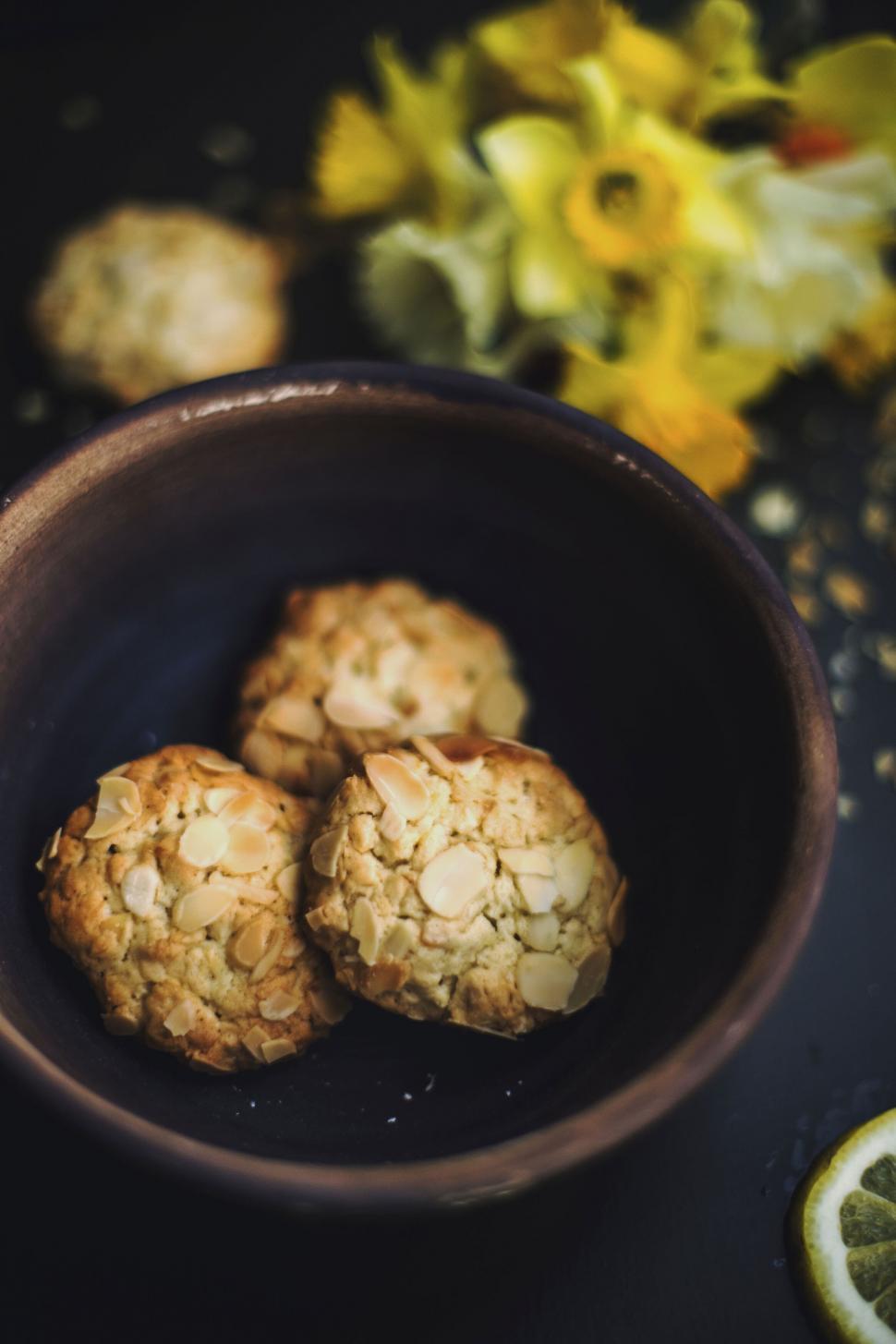Free Image of Almond cookies in a bowl with blurry flowers 