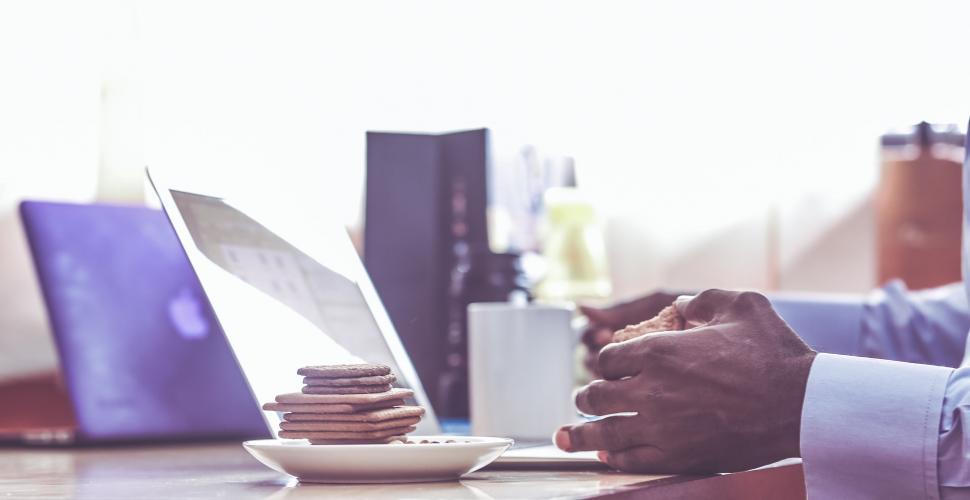 Free Image of Busy professional working on laptop with snack 