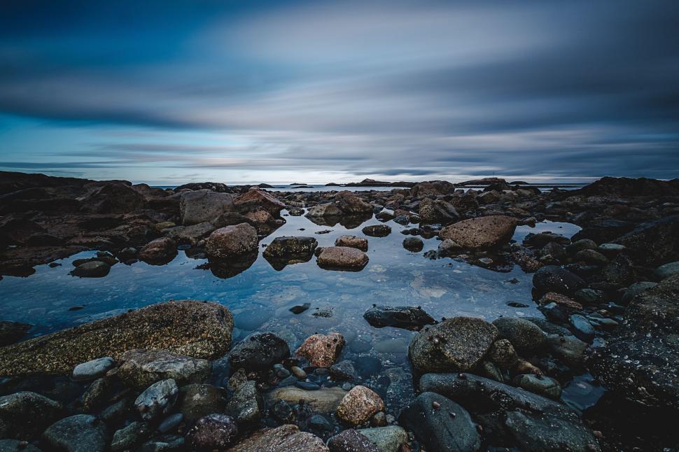 Free Image of Serene rocky beach under a cloudy sky 