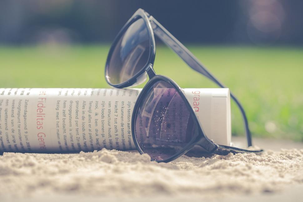 Free Image of Beach read with sunglasses and open book 