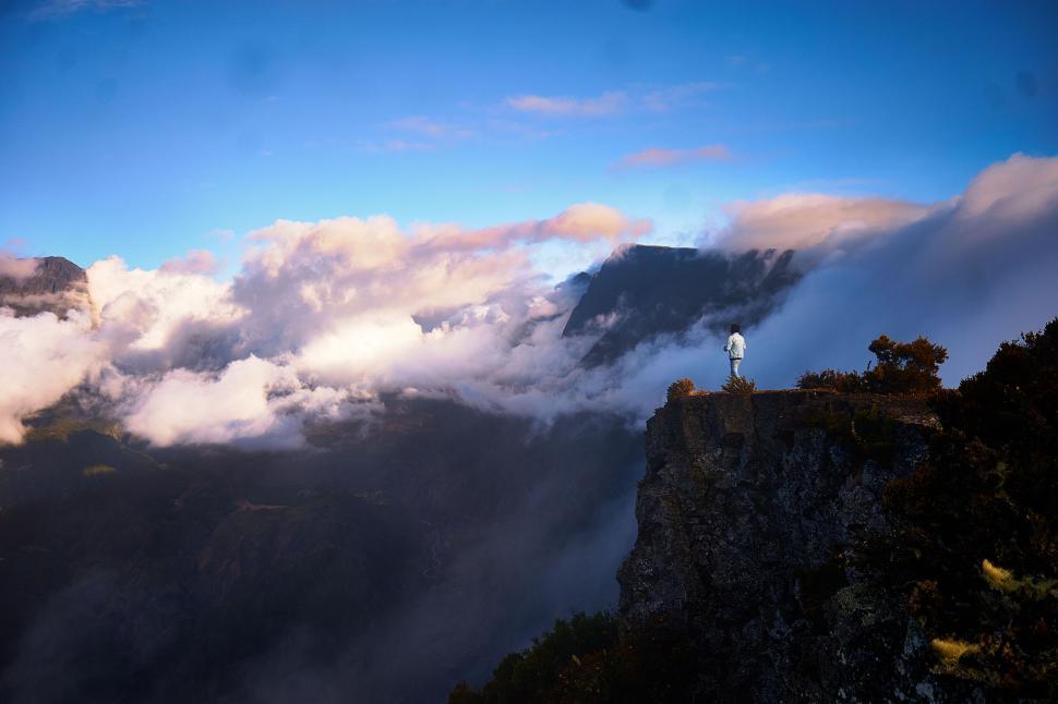Free Image of Person standing on a cliff engulfed by clouds 