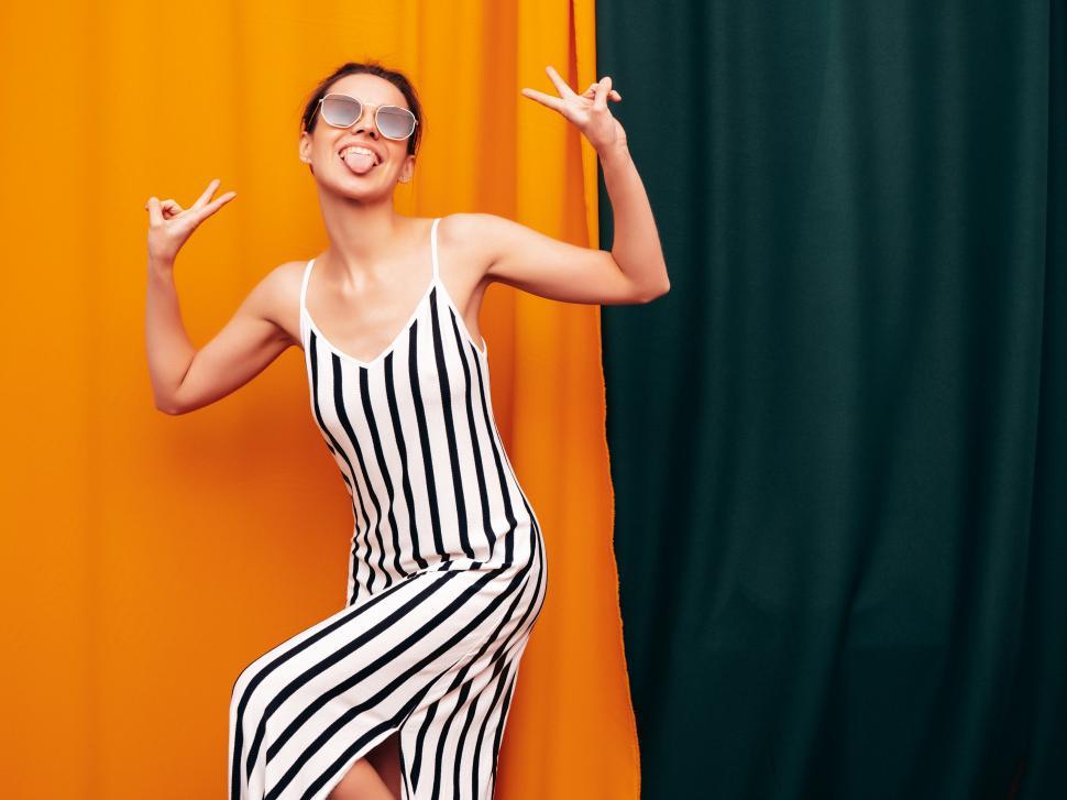 Free Image of A woman in a striped dress and sunglasses posing for a picture 
