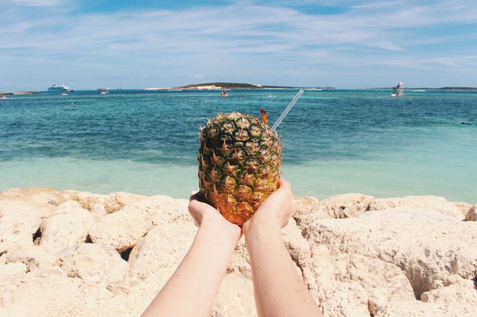 Free Image of Person holding a pineapple at the beach 