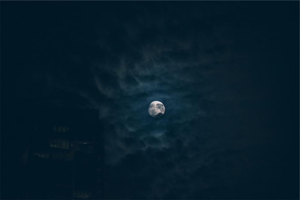 Free Image of Moon amidst clouds over city silhouette 