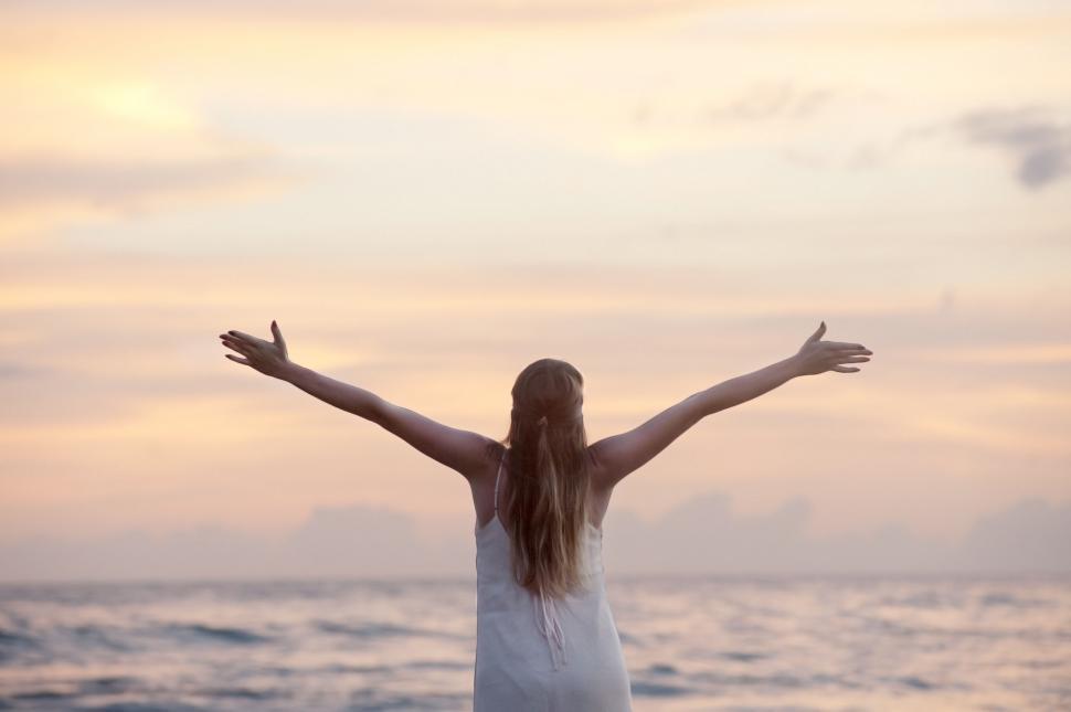 Free Image of Woman embracing sunset at the beach 