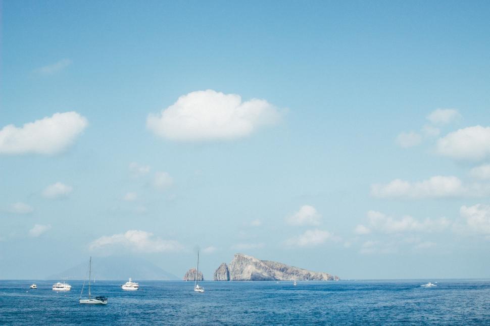 Free Image of Serene seascape with sailboats and rock island 