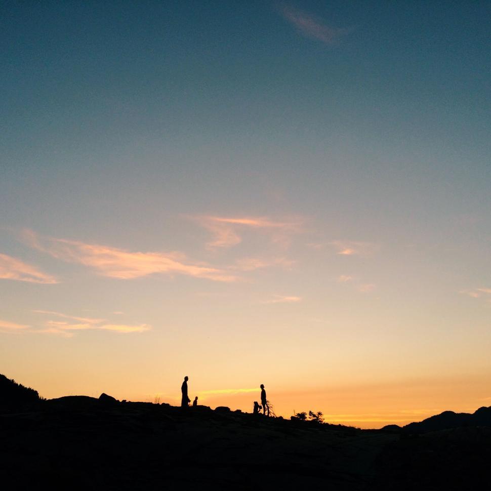 Free Image of Two silhouettes during sunset on rocky peak 