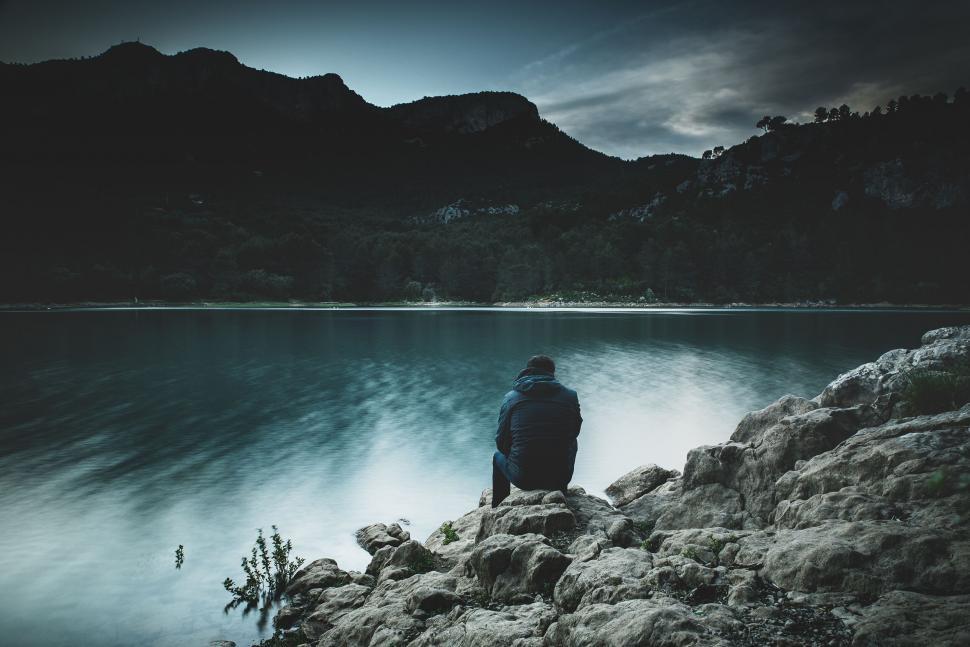 Free Image of Person sitting by tranquil mountain lake 