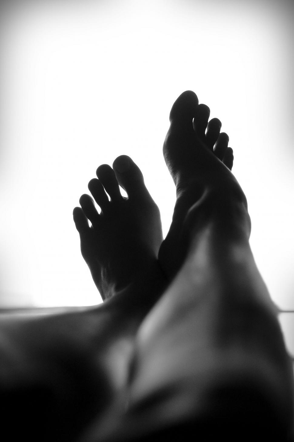 Free Image of Silhouetted human feet crossed at ankles 