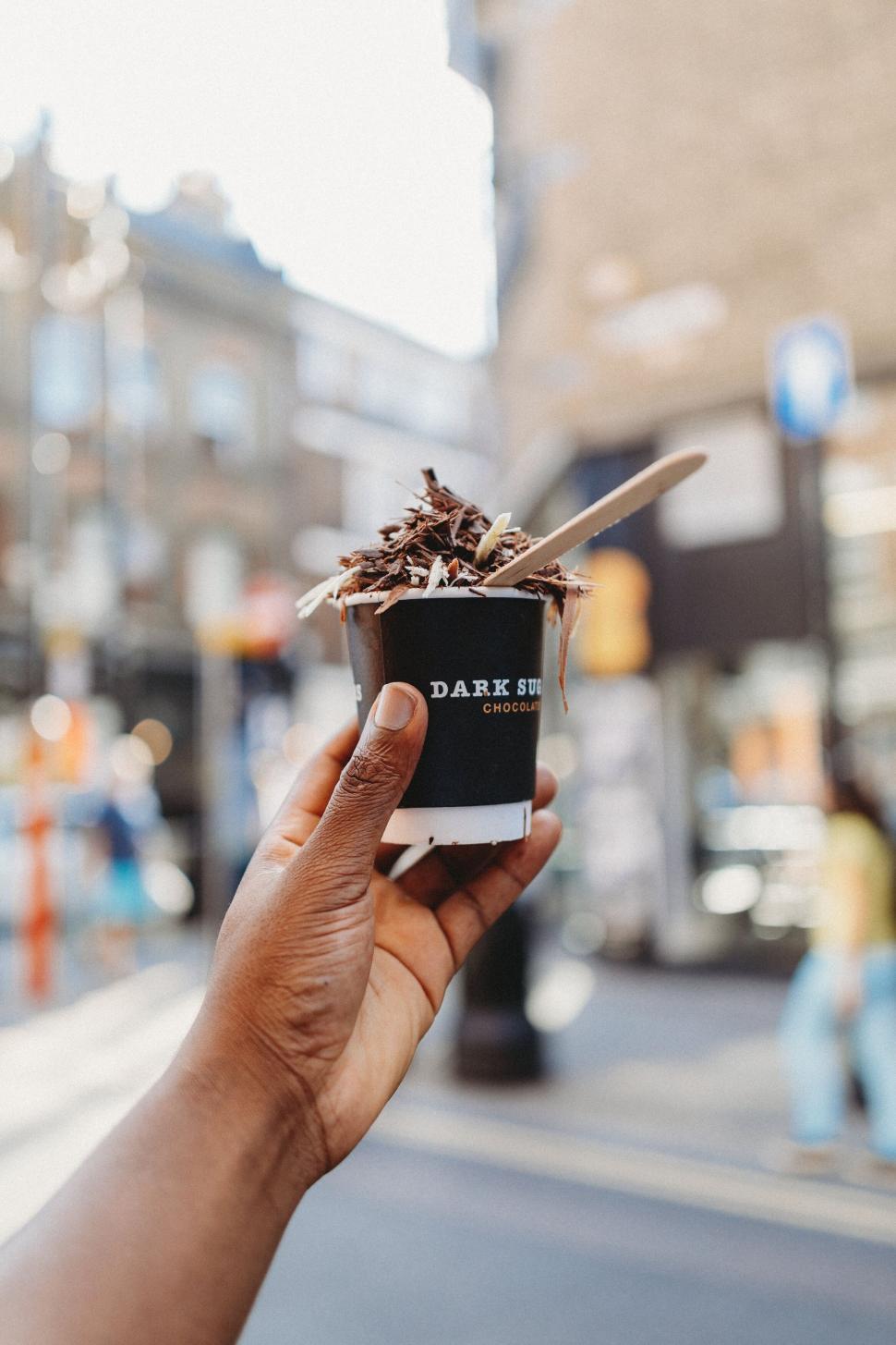 Free Image of Ice cream cup held on city street 