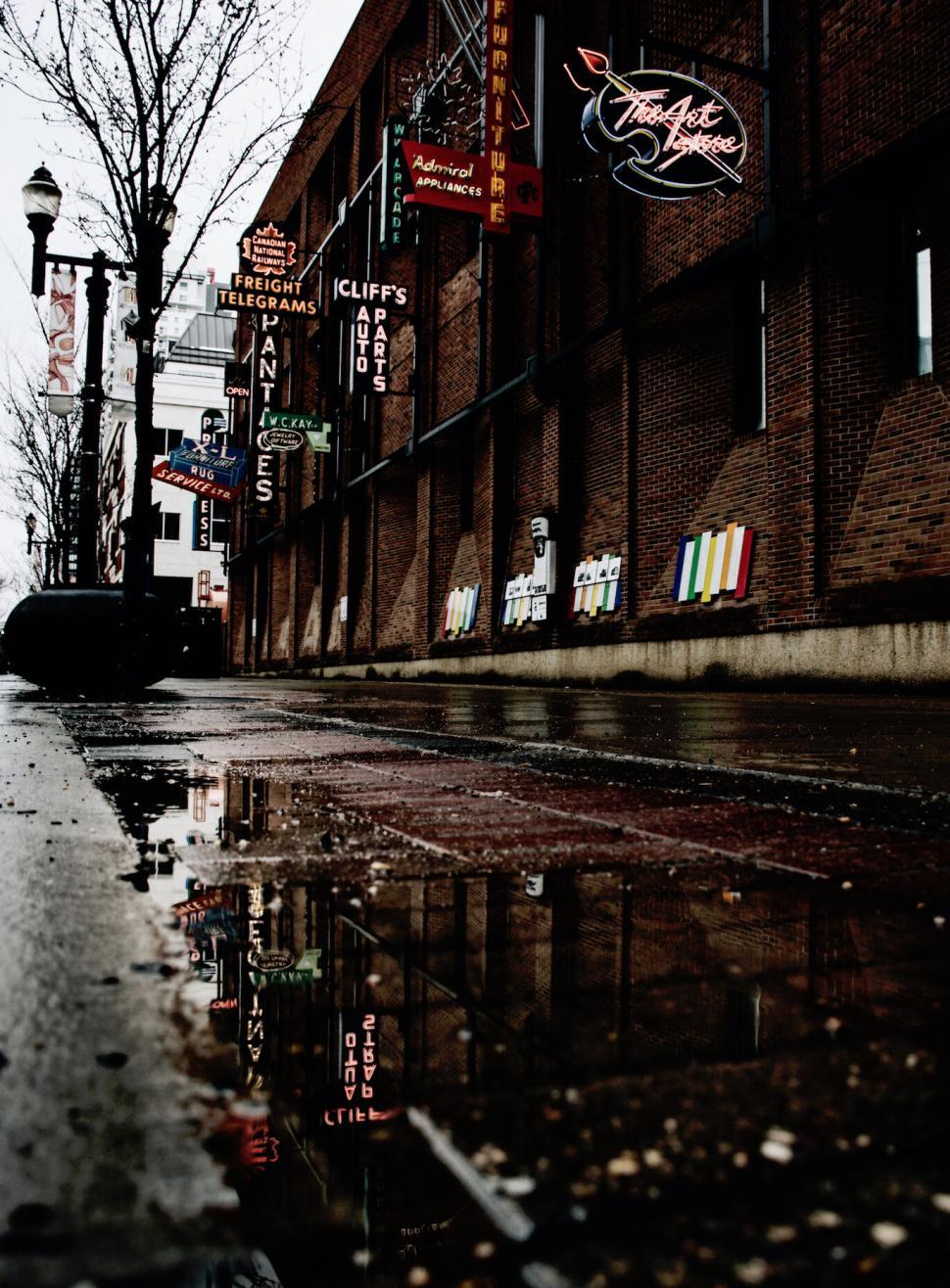 Free Image of Urban street with neon signs reflecting 