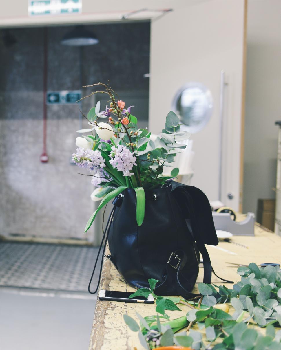Free Image of Black bag with flowers on workbench 