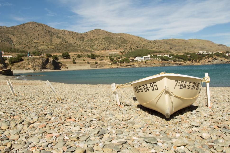 Free Image of Boat on pebble beach against hills 
