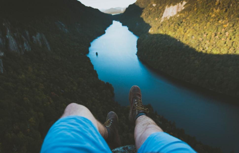 Free Image of Man sitting on edge looking at river 