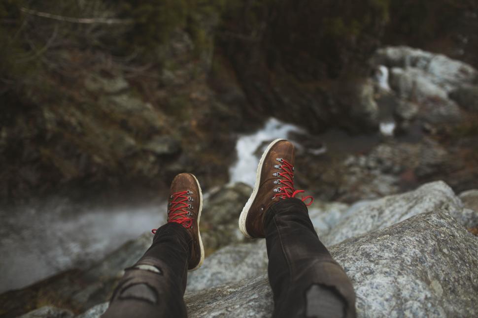 Free Image of Person on rocky edge by cascading waterfall 