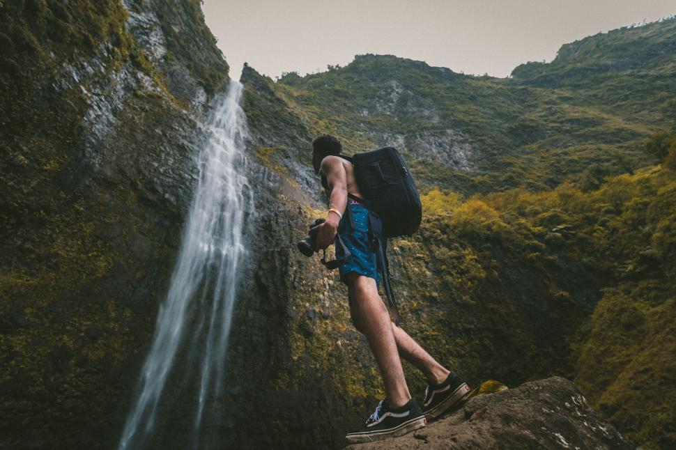 Free Image of Hiker looking at a waterfall from a cliff 