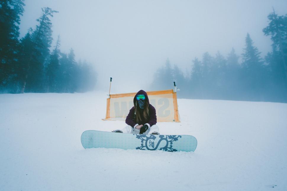 Free Image of Snowboarder sitting in snow during fog 