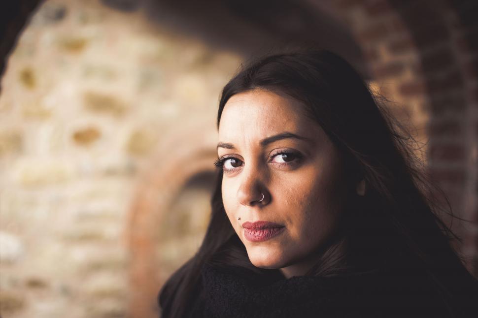 Free Image of Close-up of a thoughtful woman against brick wall 