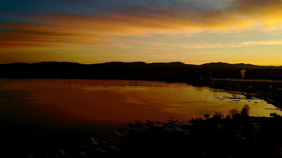 Free Image of Sunset over water with boats and hills 