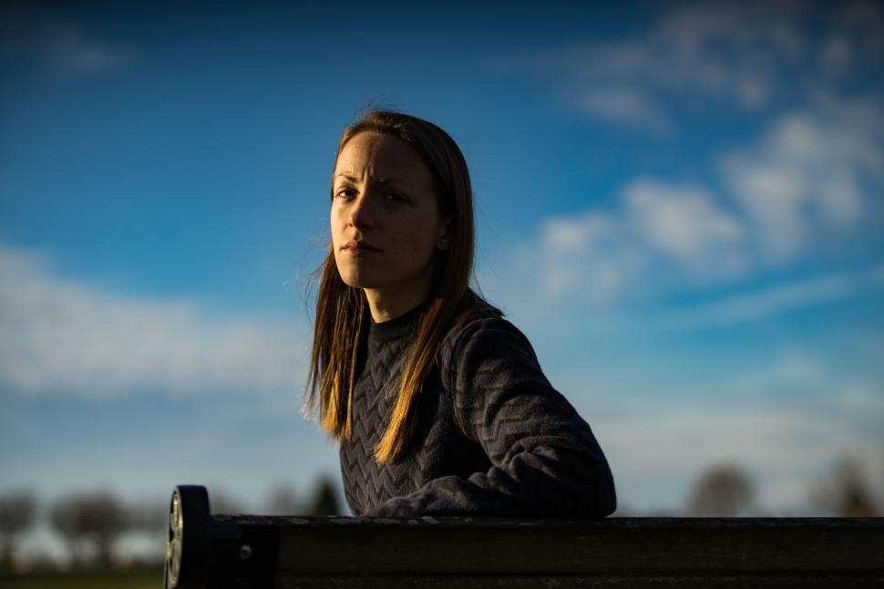 Free Image of Young person sitting on a bench outdoors 