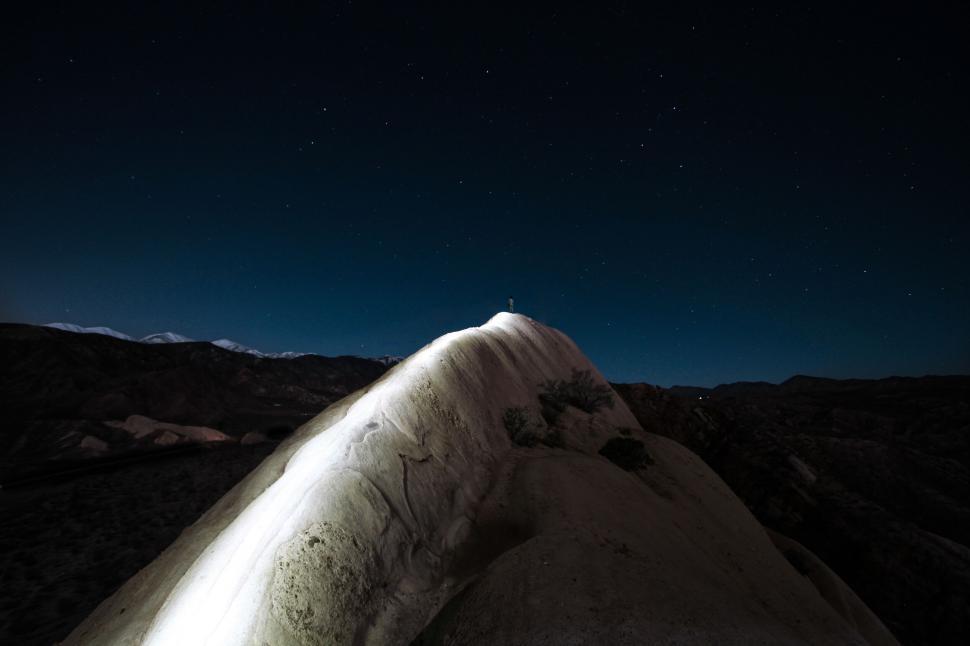 Free Image of Lone figure under the stars on rock formation 