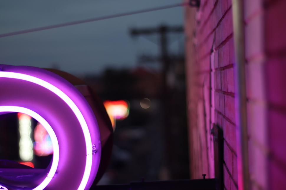 Free Image of Neon light reflecting on brick wall at dusk 
