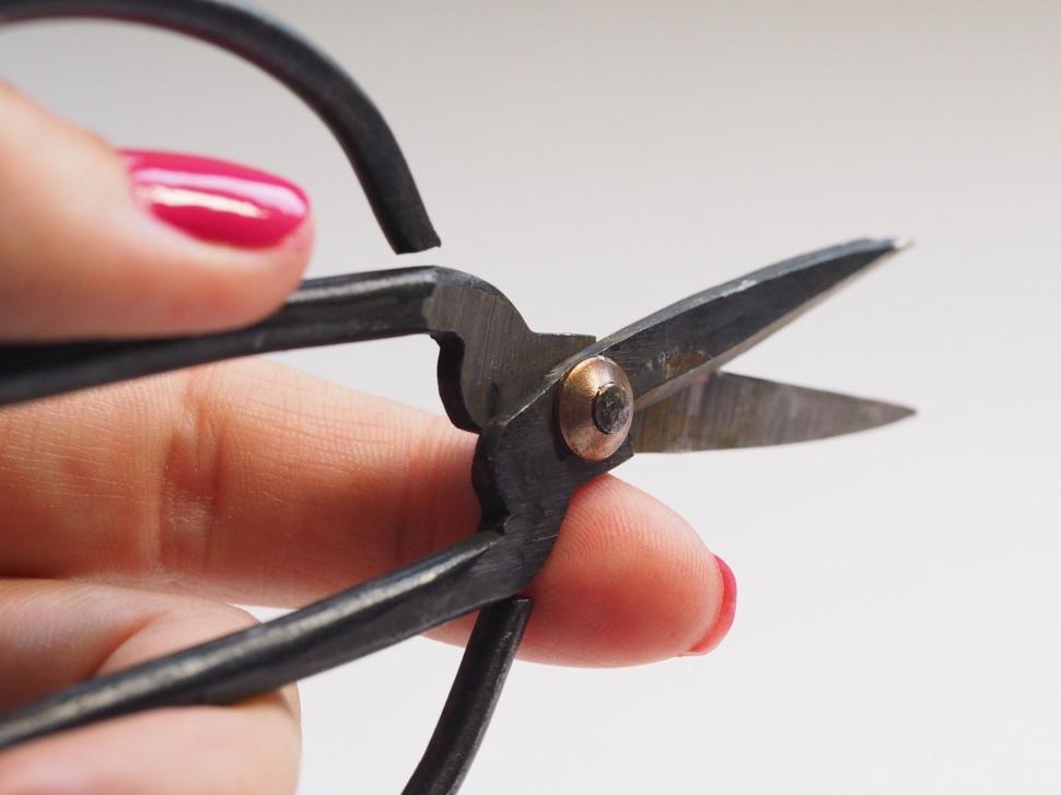 Free Image of Hand holding a pair of black scissors close-up 