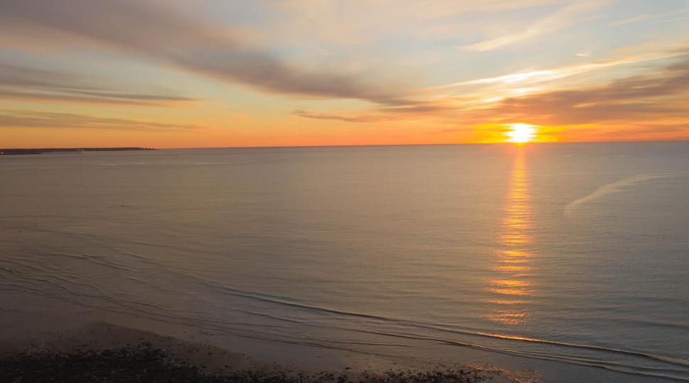 Free Image of Sunset over calm ocean with beach 