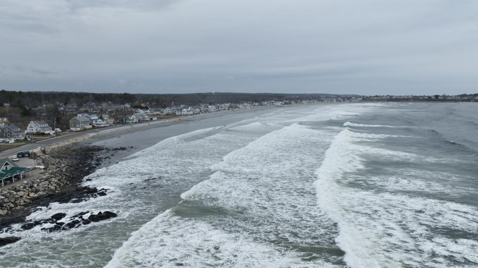 Free Image of Waves crashing on the rocky shoreline against cloudy sky 