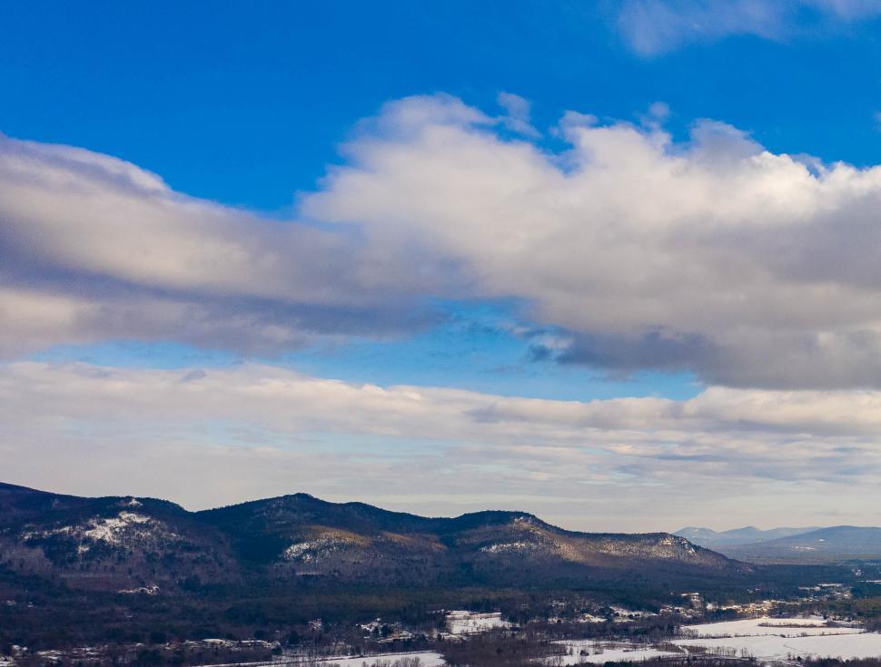 Free Image of Snow-capped mountains under wide blue sky with clouds 