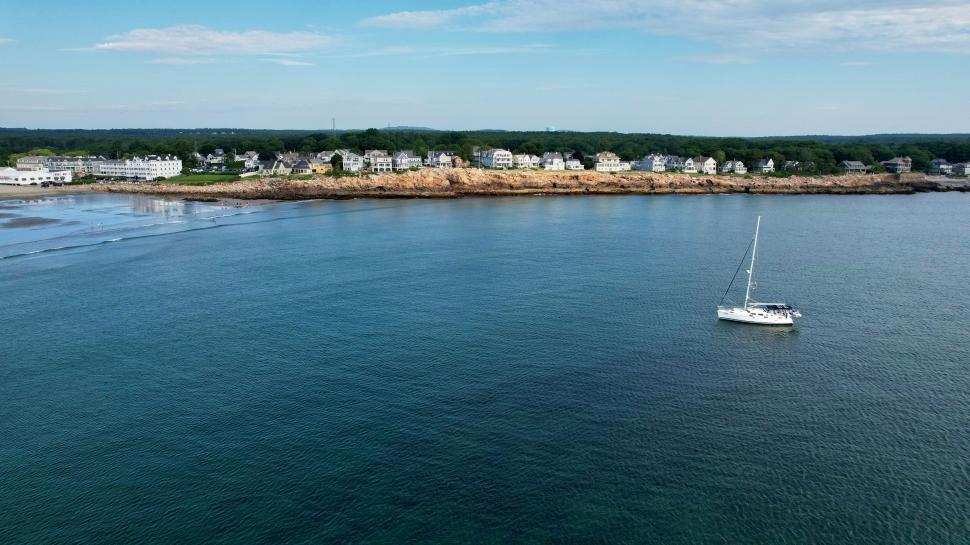 Free Image of Sailboat anchored near serene coastal village 
