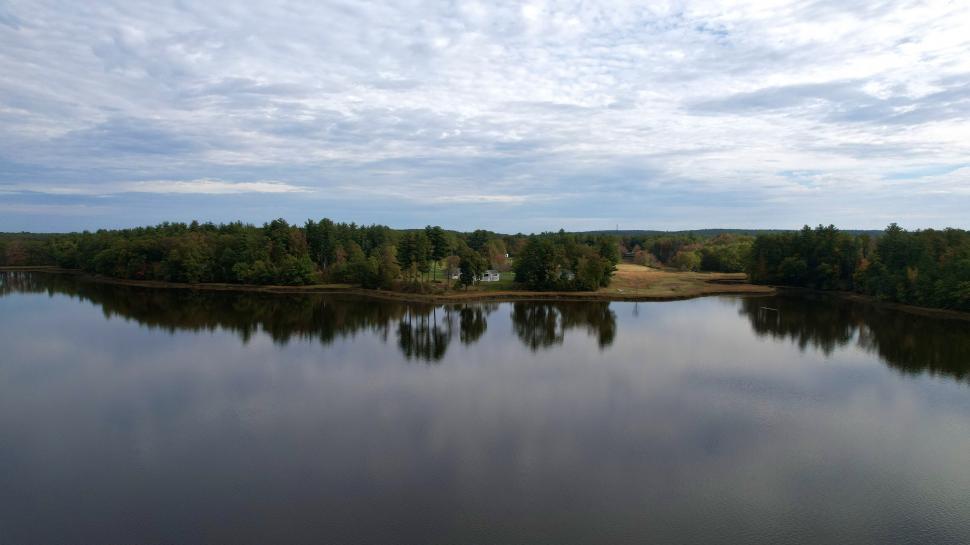 Free Image of Tranquil lake with reflective water and cloudy skies 