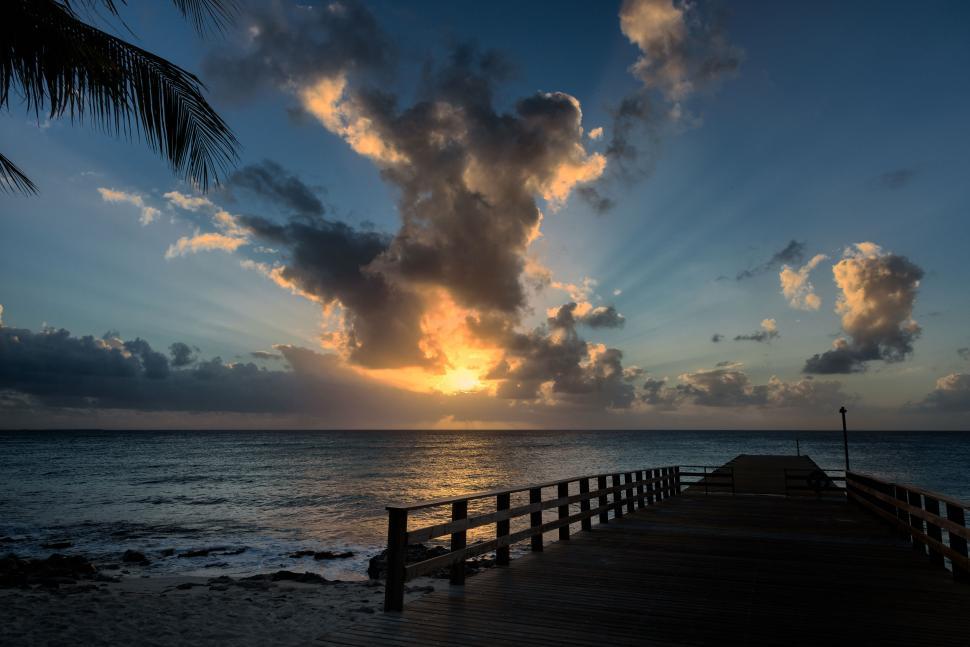Free Image of Pier Extending Into Ocean with Dramatic Cloudy Sunset Sky 