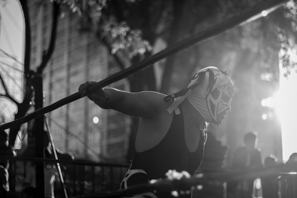 Free Image of Wrestler in mask leaning on ring ropes during match. 