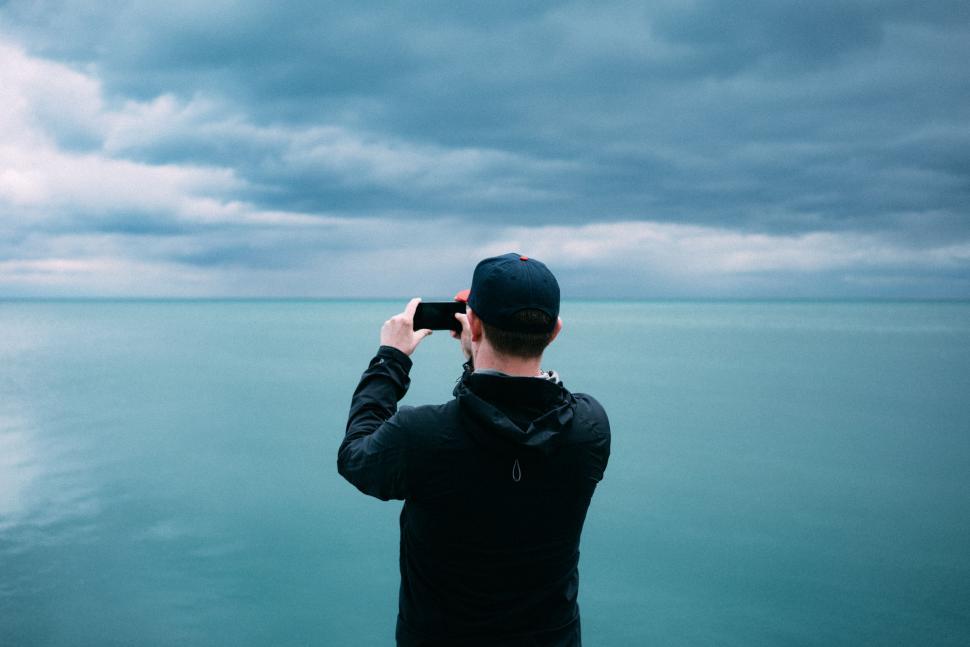 Free Image of Person photographing stormy sea under cloudy sky 
