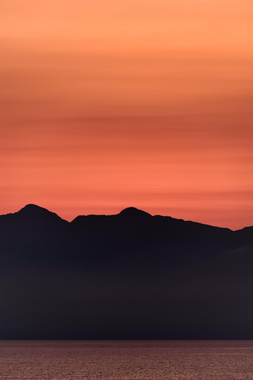 Free Image of Silhouette of mountain peaks beneath a vibrant red sky. 