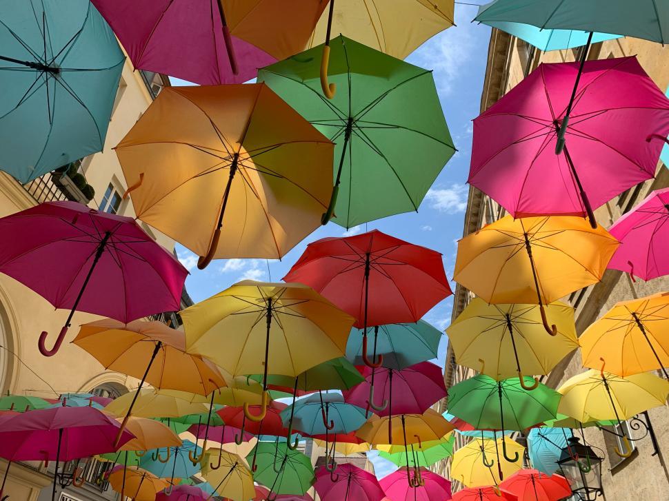Free Image of Colorful umbrellas hanging against a blue sky, vibrant art 