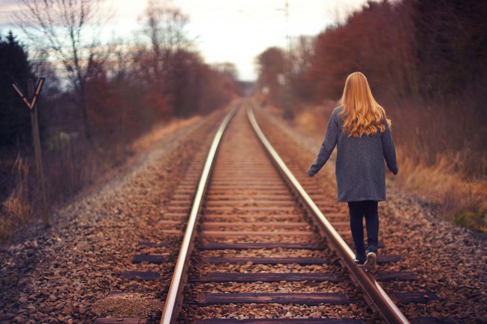 Free Image of Girl walking down an empty railway track at sunset 