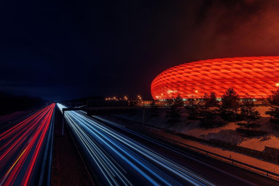 Free Image of Illuminated stadium at night beside busy highway. 